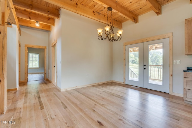 unfurnished dining area with wood ceiling, a chandelier, light hardwood / wood-style flooring, beamed ceiling, and french doors