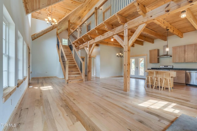 unfurnished living room featuring a notable chandelier, wood ceiling, a high ceiling, light wood-style flooring, and beamed ceiling