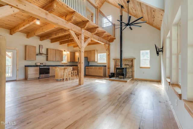 unfurnished living room with wood ceiling, beamed ceiling, a wood stove, and light wood-type flooring