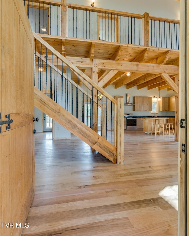 hall with beam ceiling, high vaulted ceiling, and light wood-type flooring