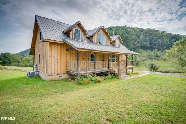 view of front of property featuring metal roof, crawl space, central AC unit, a front yard, and covered porch