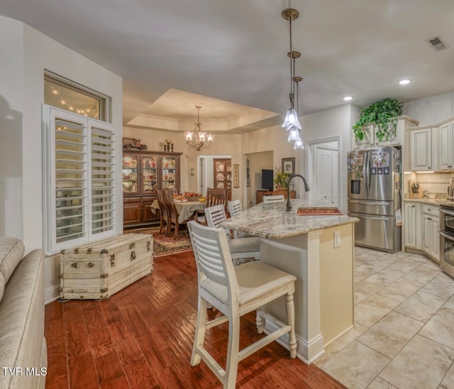 kitchen featuring pendant lighting, a kitchen breakfast bar, light wood-type flooring, an island with sink, and stainless steel appliances