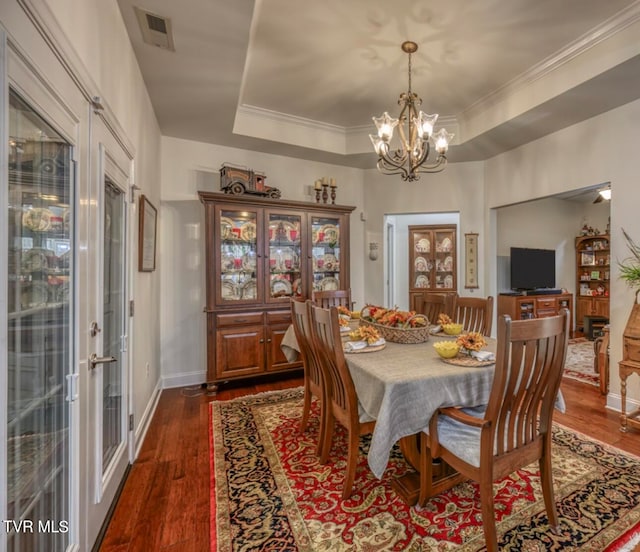 dining room with a raised ceiling, french doors, dark hardwood / wood-style floors, and an inviting chandelier