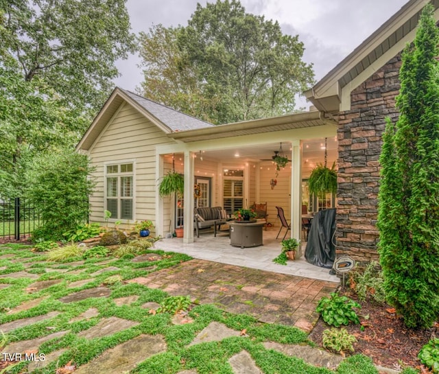 rear view of property with an outdoor living space, a patio, and ceiling fan