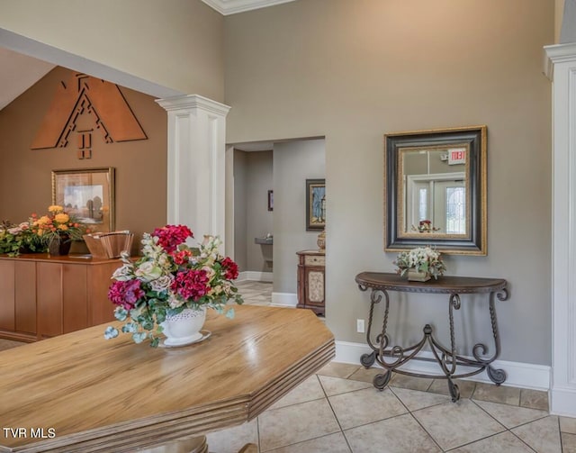 tiled dining room featuring decorative columns and crown molding