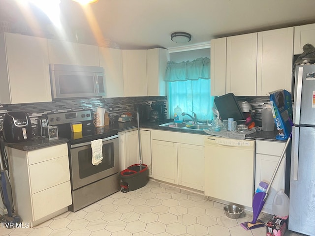 kitchen with appliances with stainless steel finishes, white cabinetry, sink, and tasteful backsplash