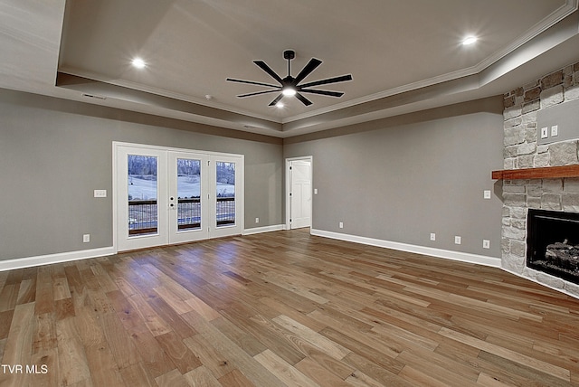 unfurnished living room with light hardwood / wood-style flooring, a tray ceiling, and a fireplace