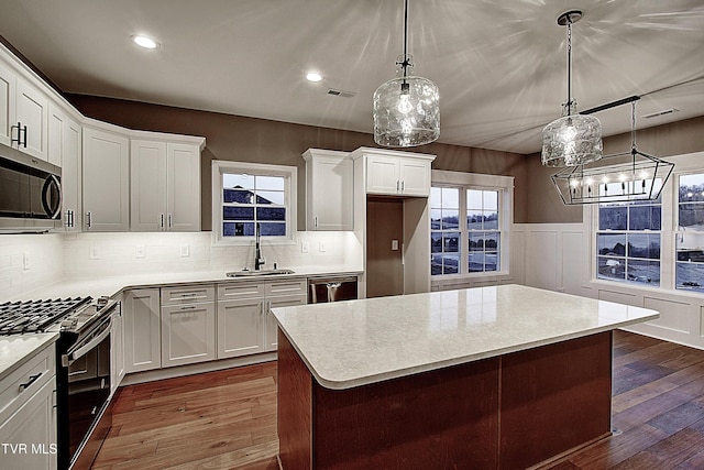 kitchen featuring white cabinetry, sink, dark hardwood / wood-style flooring, hanging light fixtures, and stainless steel appliances