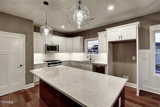 kitchen with appliances with stainless steel finishes, white cabinets, and decorative light fixtures