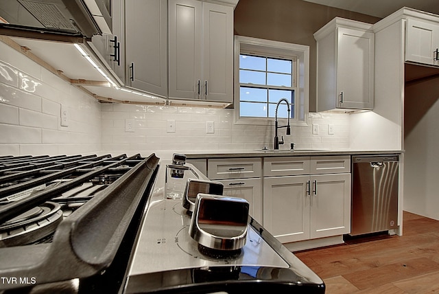 kitchen with white cabinetry, dishwasher, sink, and light hardwood / wood-style flooring