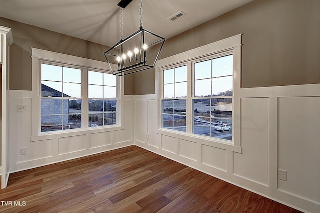 unfurnished dining area with hardwood / wood-style floors and a chandelier