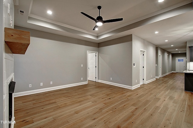 unfurnished living room with ornamental molding, a tray ceiling, ceiling fan, and light hardwood / wood-style flooring