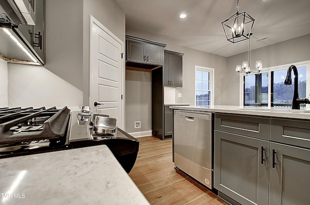 kitchen with sink, a chandelier, hanging light fixtures, light wood-type flooring, and stainless steel dishwasher