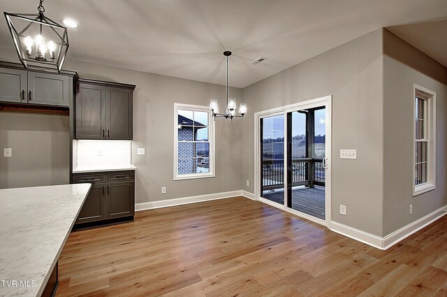 unfurnished dining area featuring a chandelier and light hardwood / wood-style floors