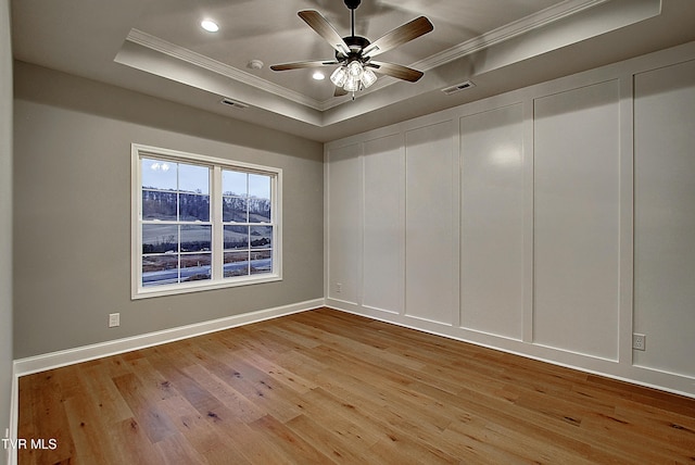 spare room featuring a raised ceiling, crown molding, ceiling fan, and light hardwood / wood-style floors