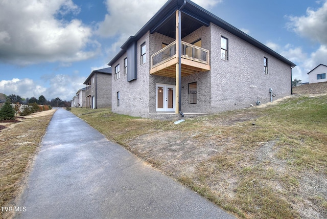 view of side of property with a balcony and a yard