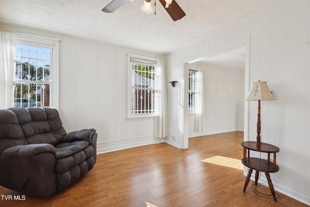 living area featuring wood-type flooring, a textured ceiling, and ceiling fan