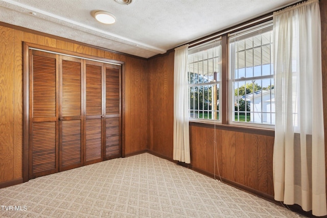 interior space featuring wood walls, a closet, and a textured ceiling