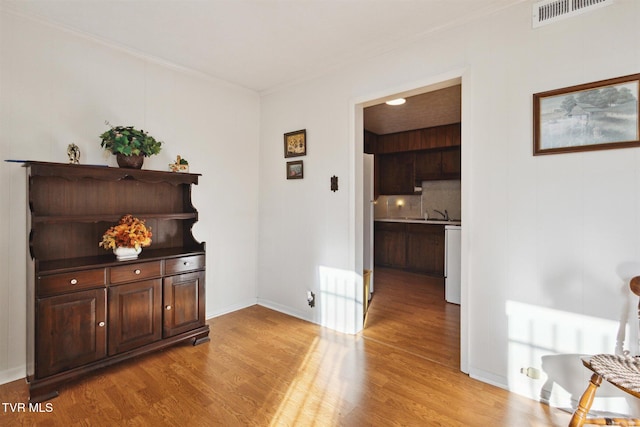 corridor with crown molding and light hardwood / wood-style flooring