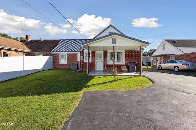 view of front of house with a porch, a front yard, and central AC unit