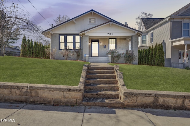 bungalow-style home with a yard and covered porch