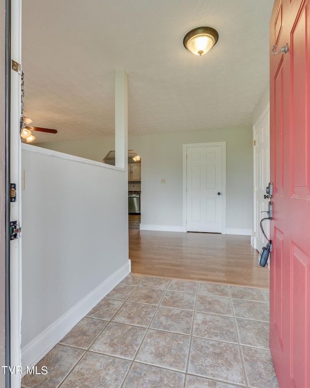 foyer entrance featuring ceiling fan, a textured ceiling, light hardwood / wood-style flooring, and vaulted ceiling