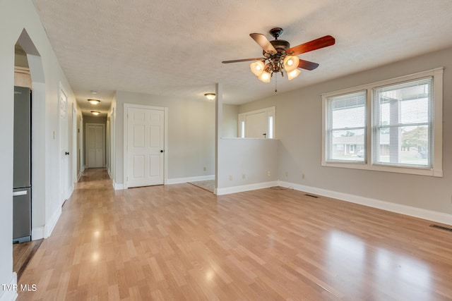 spare room with light hardwood / wood-style flooring, ceiling fan, and a textured ceiling