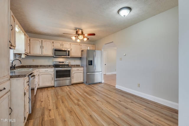 kitchen featuring a textured ceiling, sink, light hardwood / wood-style flooring, appliances with stainless steel finishes, and ceiling fan