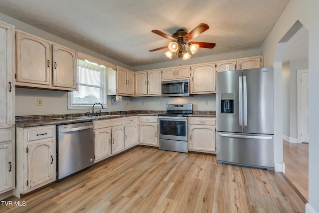 kitchen with appliances with stainless steel finishes, light hardwood / wood-style floors, sink, and ceiling fan