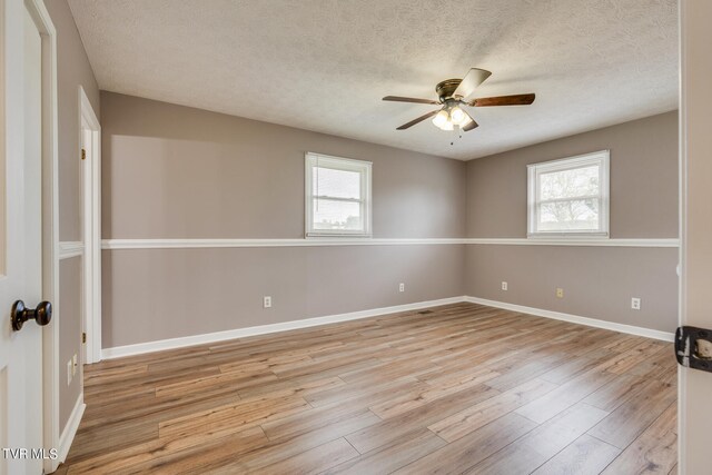 empty room featuring light hardwood / wood-style floors, ceiling fan, plenty of natural light, and a textured ceiling