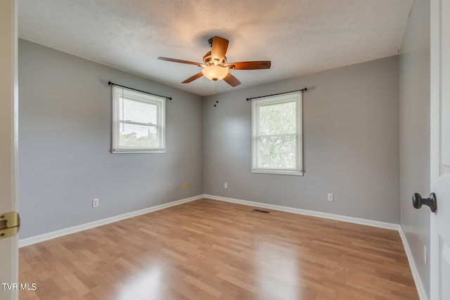 spare room with light hardwood / wood-style floors, ceiling fan, and a textured ceiling