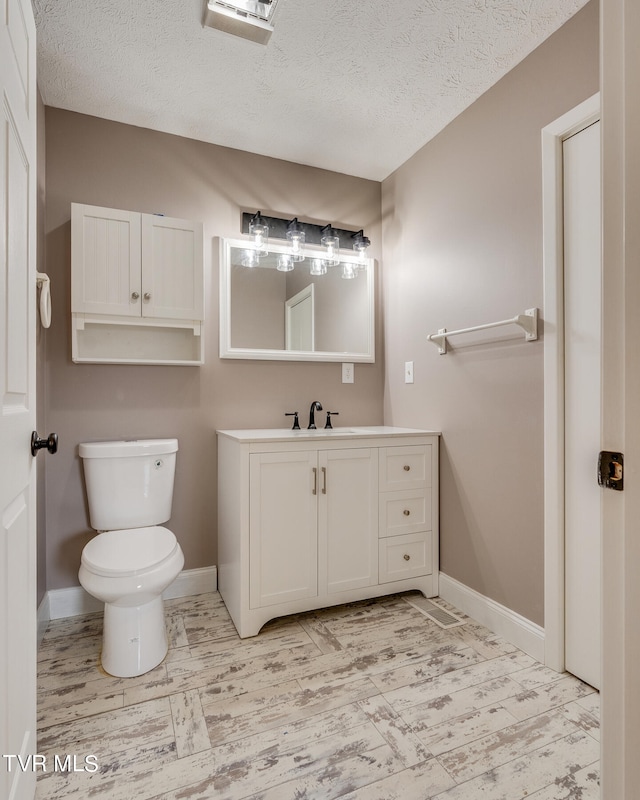 bathroom featuring a textured ceiling, vanity, and toilet