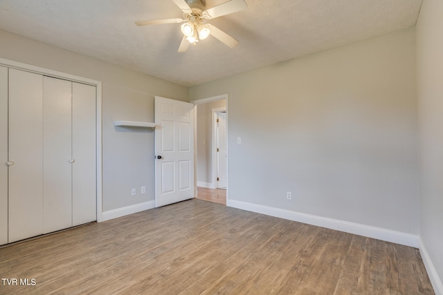 unfurnished bedroom featuring ceiling fan, a textured ceiling, light wood-type flooring, and a closet