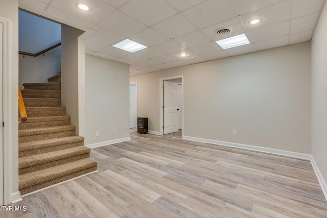 basement with light hardwood / wood-style floors and a paneled ceiling