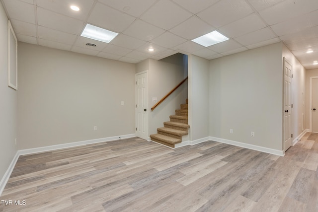 basement featuring a drop ceiling and light hardwood / wood-style floors