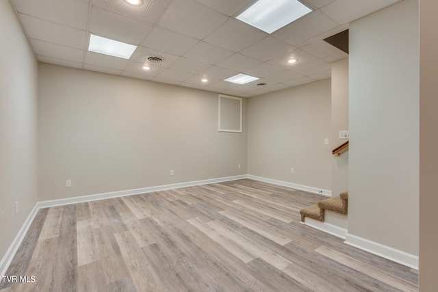 basement featuring a drop ceiling and light hardwood / wood-style floors