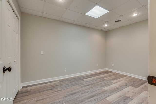 spare room featuring light wood-type flooring and a paneled ceiling