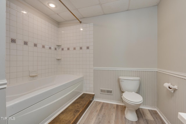 bathroom with tiled shower / bath combo, toilet, and hardwood / wood-style flooring