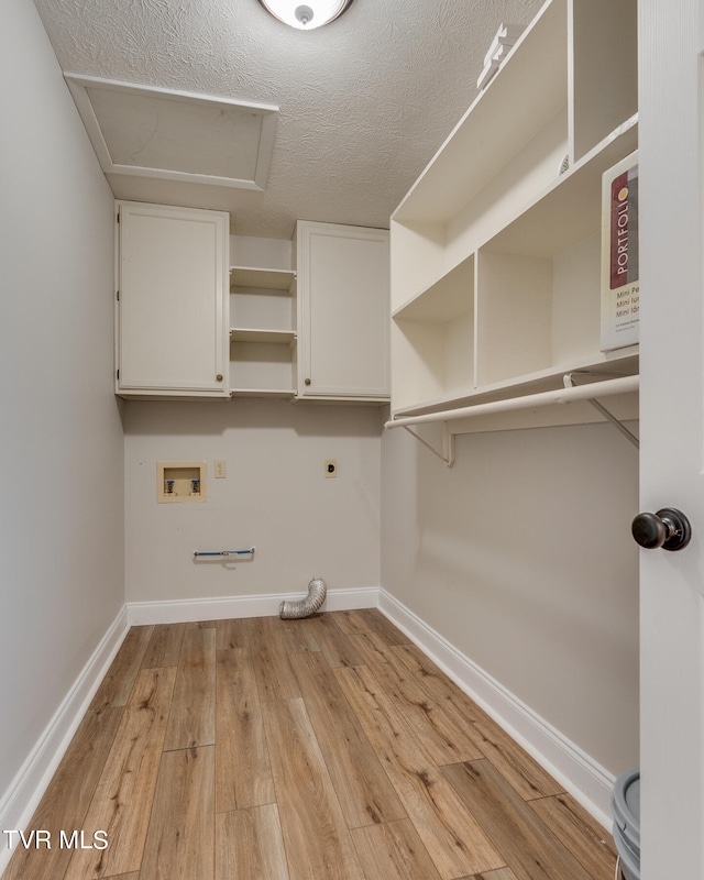 laundry room featuring hookup for an electric dryer, a textured ceiling, cabinets, hookup for a washing machine, and light hardwood / wood-style floors