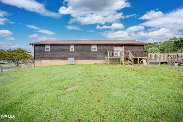 rear view of house featuring a wooden deck and a lawn