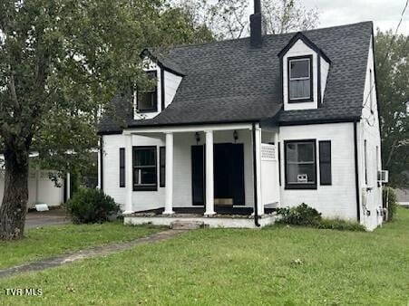 new england style home featuring a front yard and covered porch