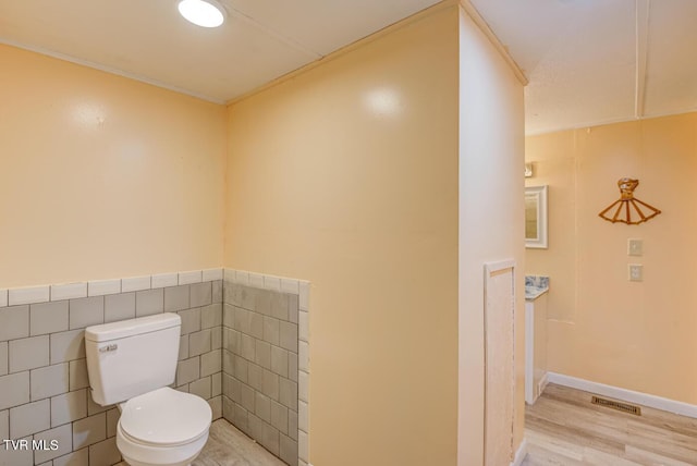 bathroom featuring toilet, visible vents, tile walls, and wood finished floors