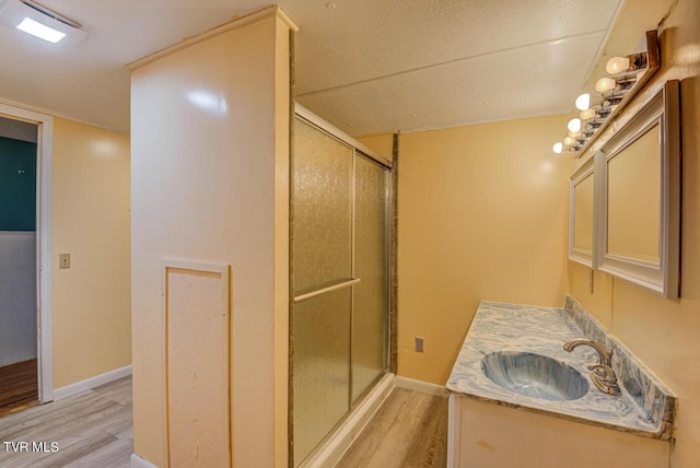bathroom featuring baseboards, wood finished floors, a stall shower, and vanity