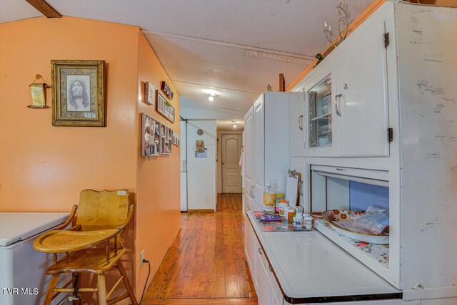 hallway featuring light hardwood / wood-style floors and vaulted ceiling