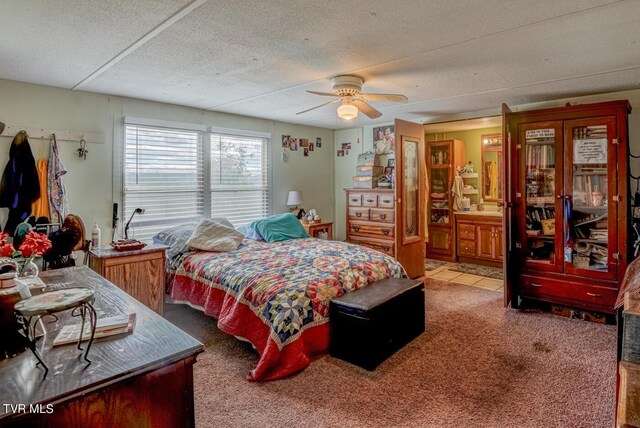 bedroom with ceiling fan, a textured ceiling, ensuite bath, and carpet flooring