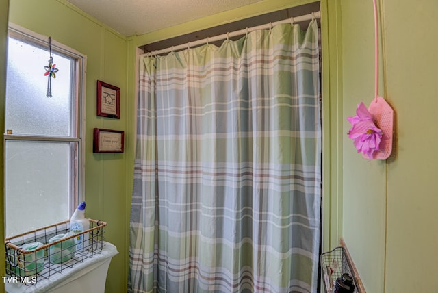 bathroom with a textured ceiling, walk in shower, and toilet