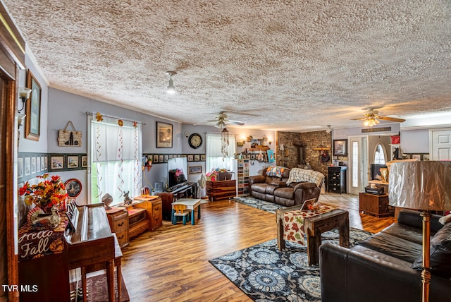 living room featuring ceiling fan, hardwood / wood-style flooring, a textured ceiling, and a wealth of natural light