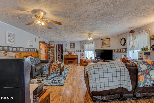 living room featuring a textured ceiling, wood finished floors, a ceiling fan, and ornamental molding