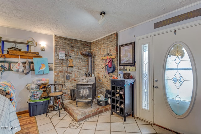 foyer entrance with a wood stove, brick wall, a textured ceiling, light hardwood / wood-style flooring, and crown molding