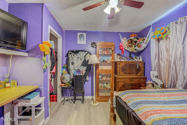 bedroom featuring light wood-type flooring, ceiling fan, and a textured ceiling